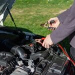 Mechanik na zewnątrz podłącza kable rozruchowe do akumulatora auta