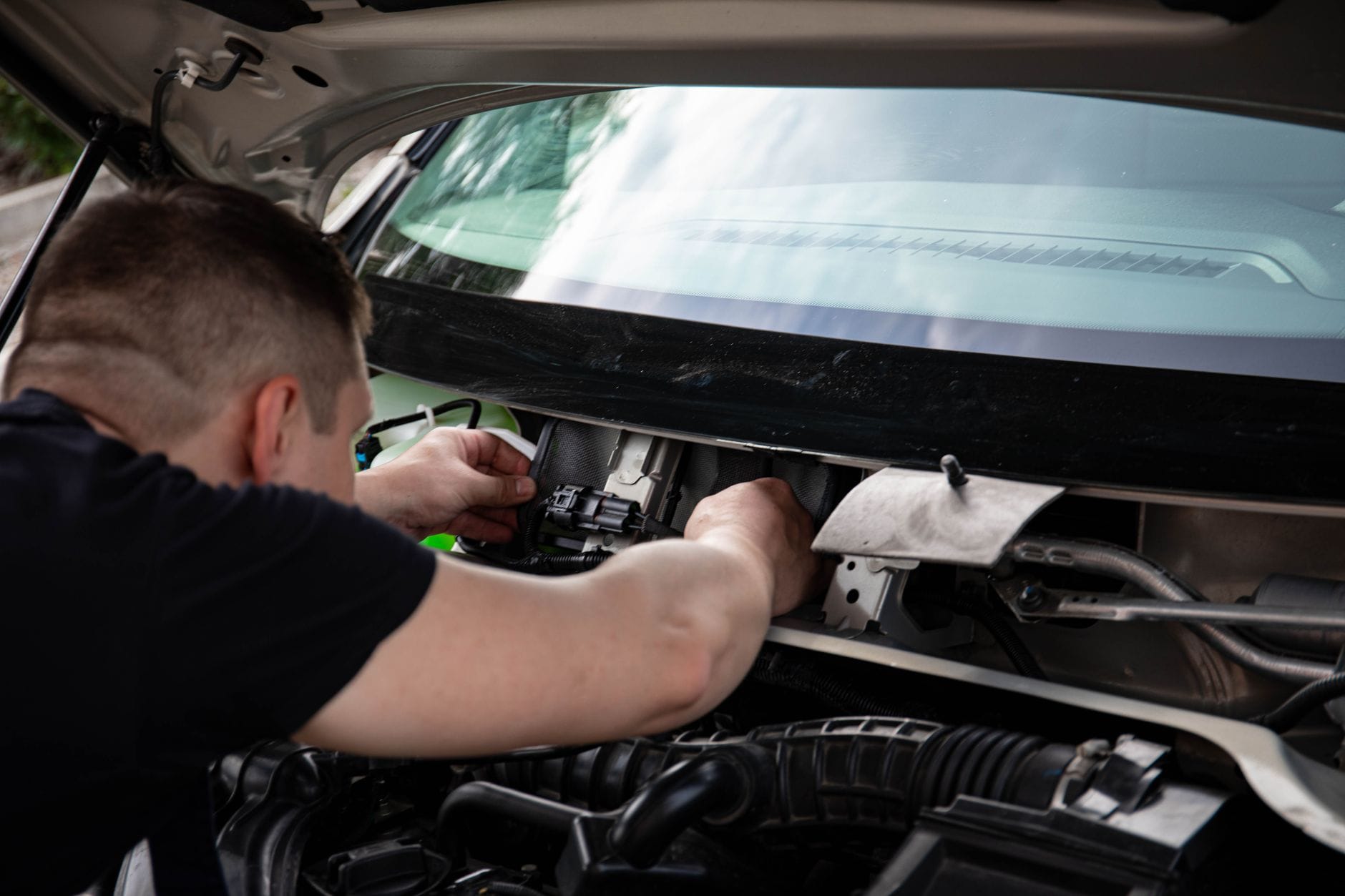 Mechanik diagnozuje instalację elektryczną w komorze silnika samochodu