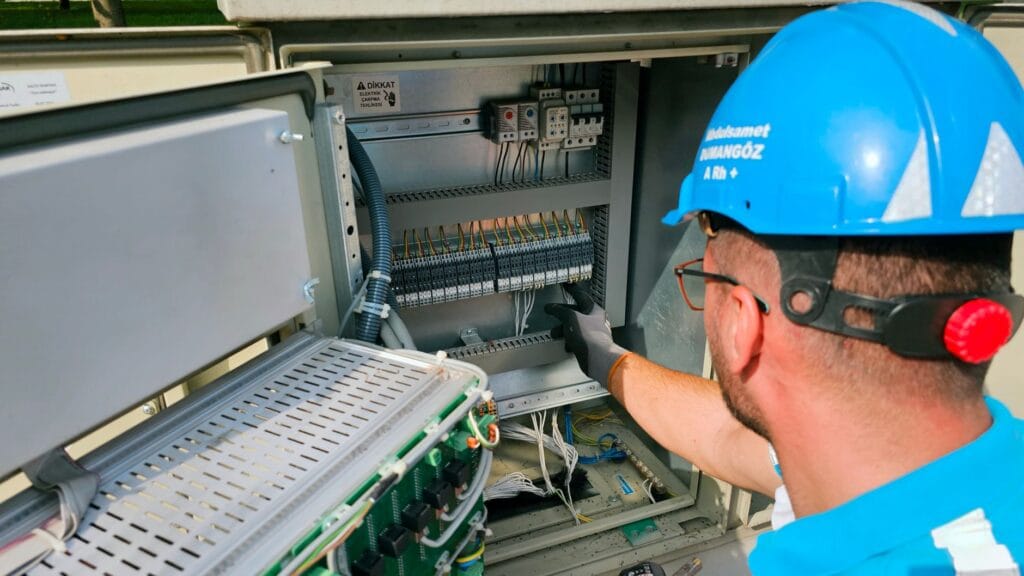 Elektryk pracuje przy zewnętrznej skrzynce bezpiecznikowej